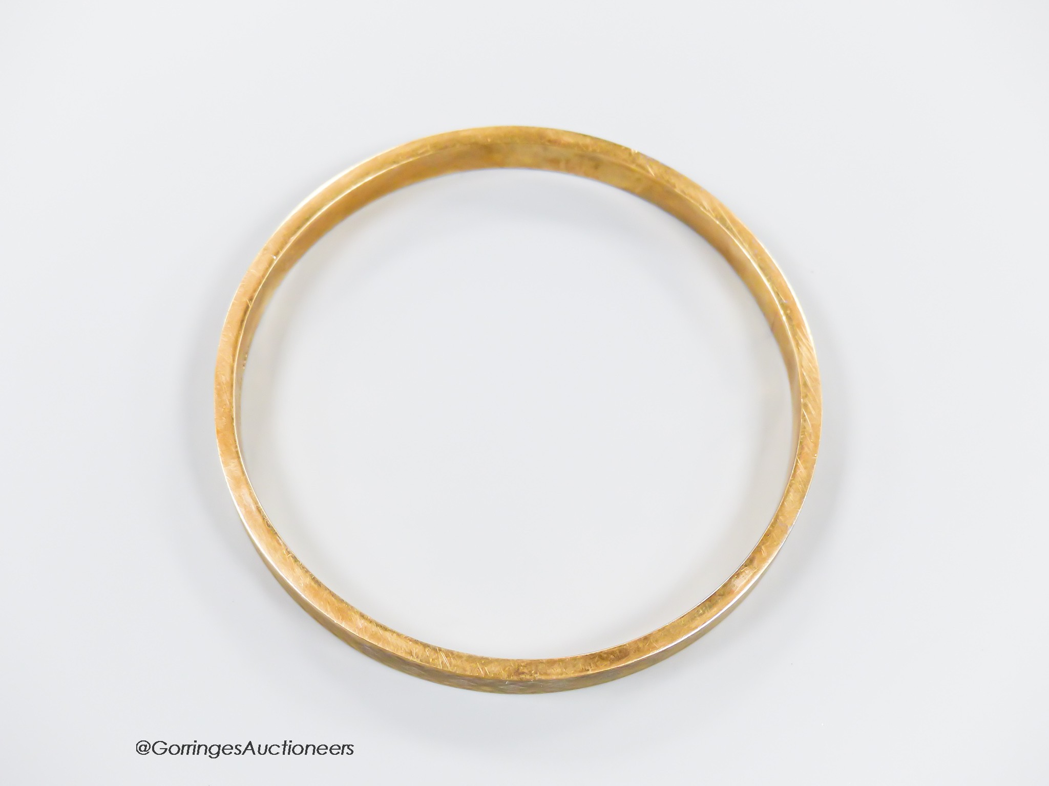 A 1920's engine turned 9ct gold bangle, interior diameter 76mm, 11.9 grams.